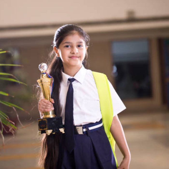 Little girl holding trophy at school campus